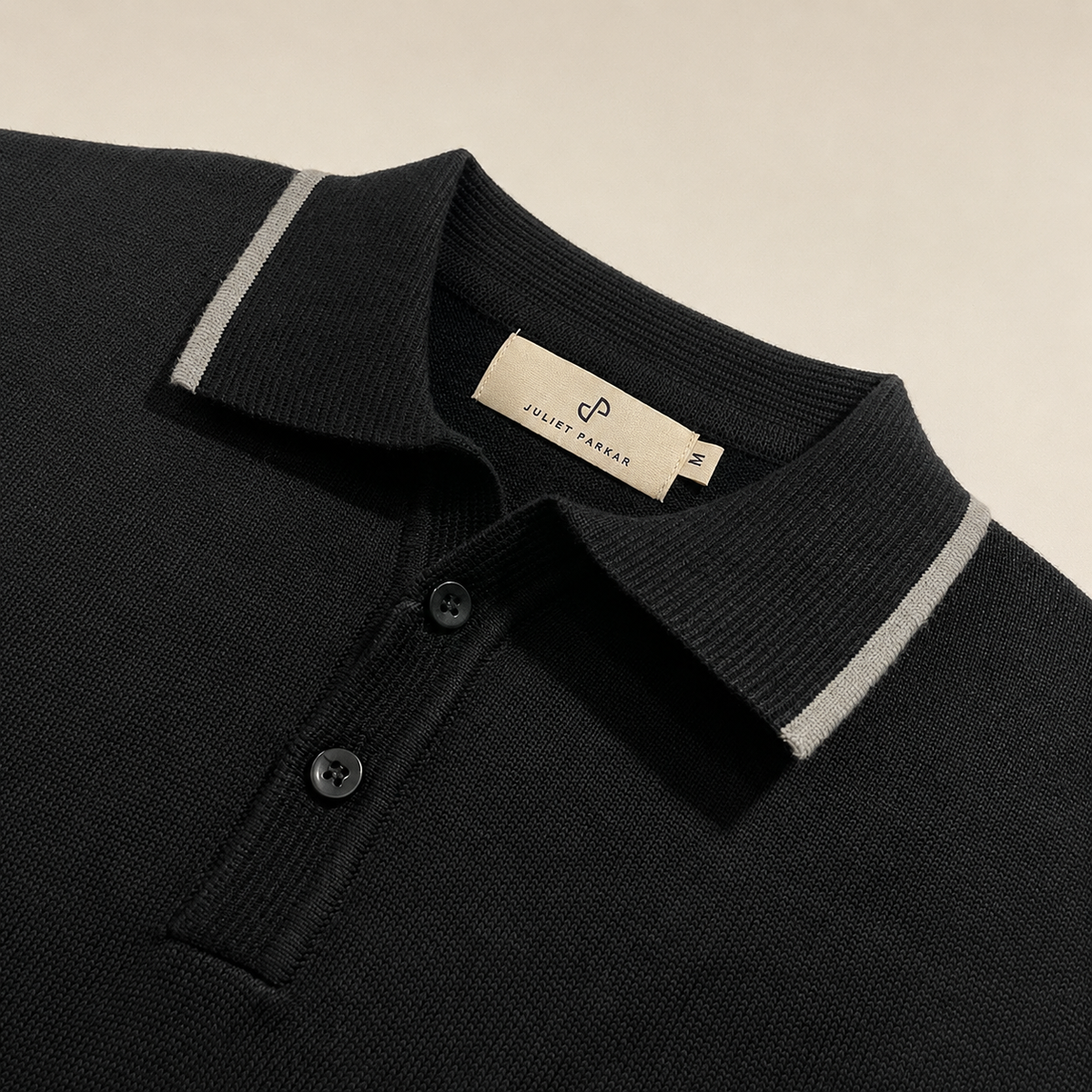 Close-up of the collar and button placket on the Men's Black Classic Polo in 100% cotton piqué by Juliet Parkar