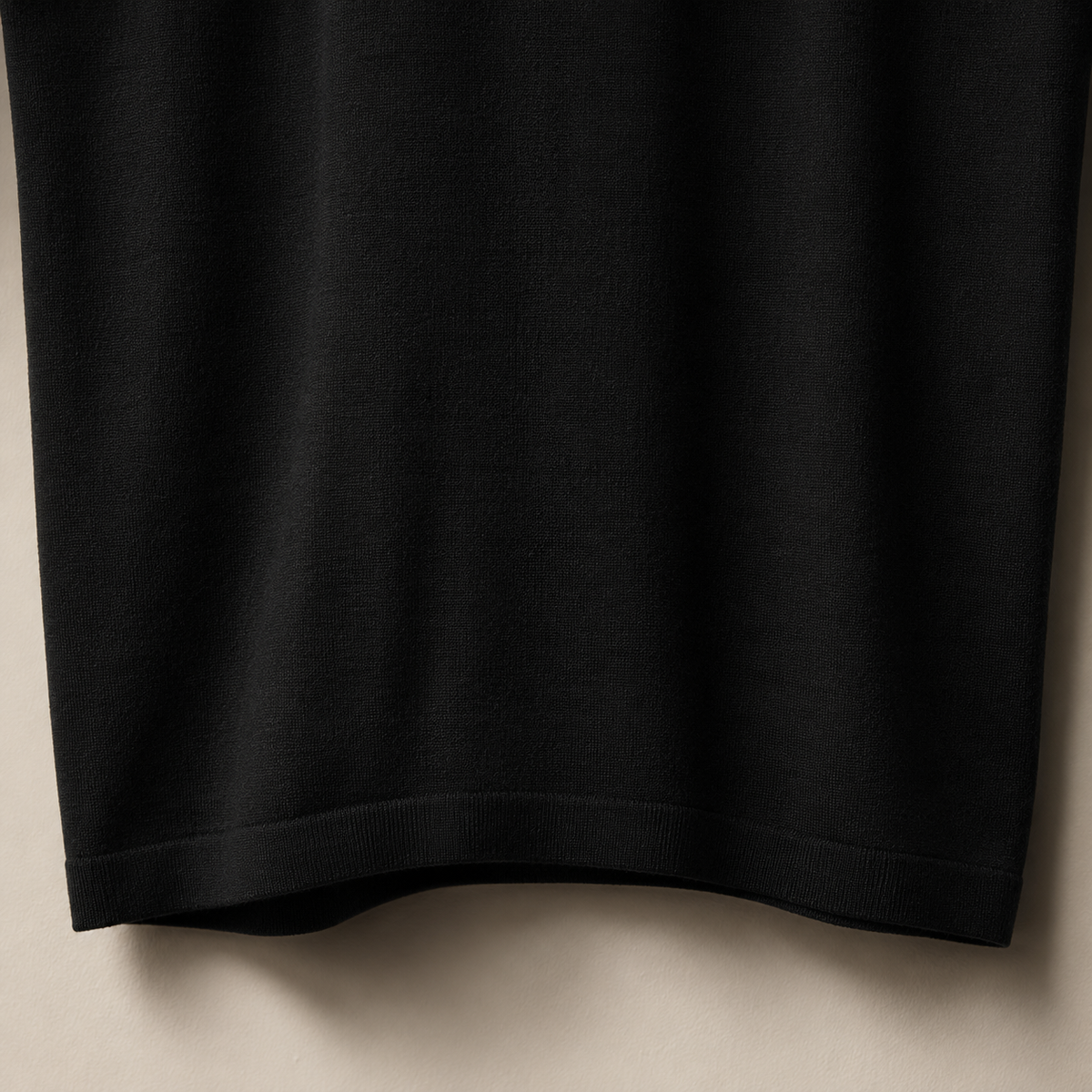 Close-up of the 100% cotton piqué fabric and bottom hem stitching on the Men's Black Classic Polo by Juliet Parkar