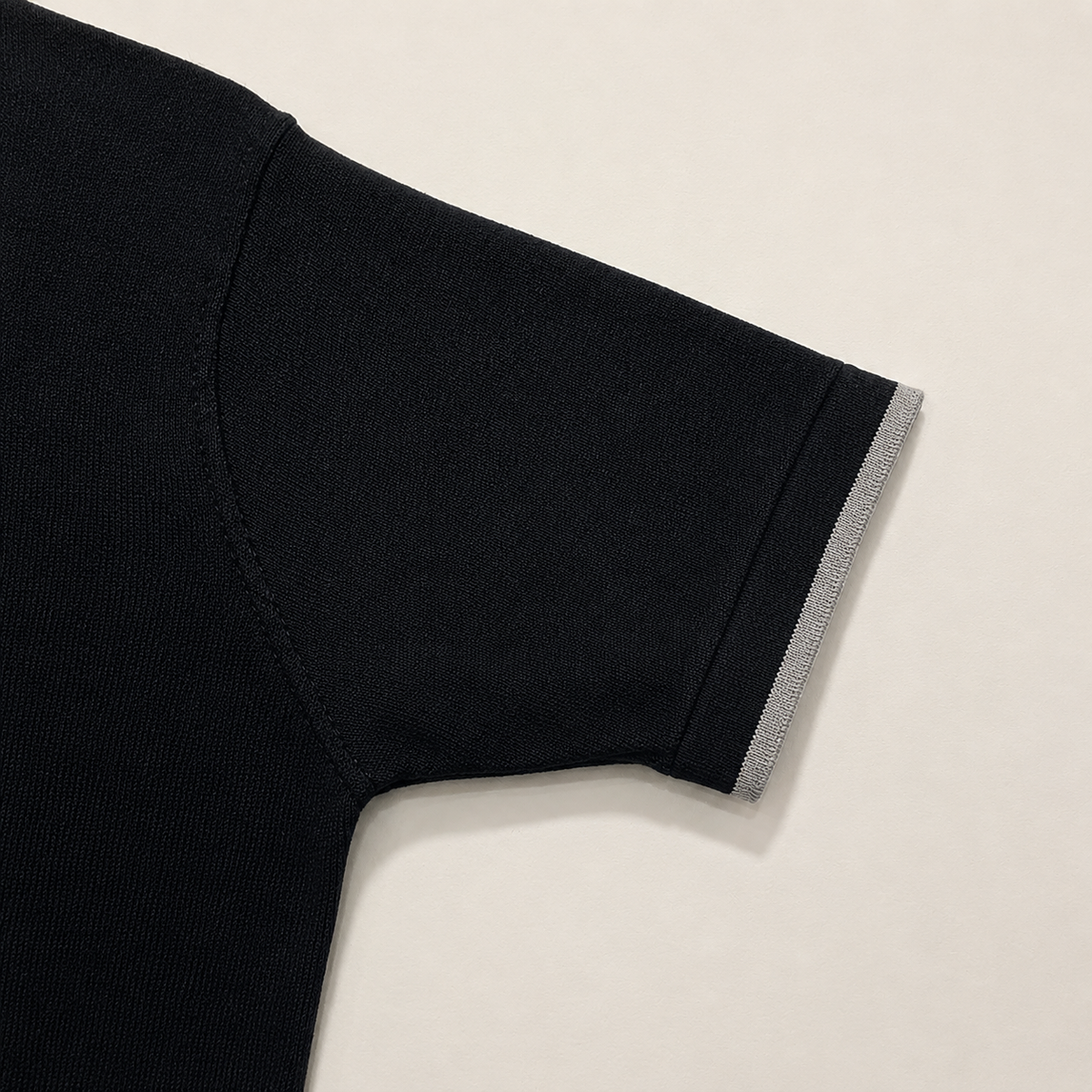 Close-up of the short sleeve with ribbed cuff on the Men's Black Classic Polo in 100% cotton piqué by Juliet Parkar
