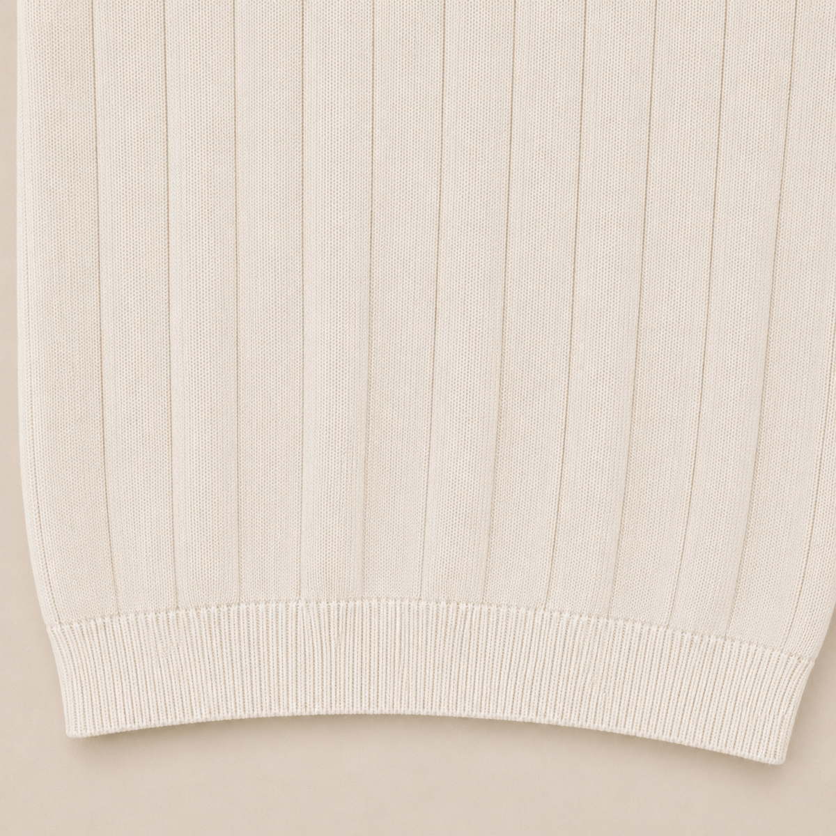 Close-up of the 100% cotton fabric and bottom hem stitching on the Men's Pearl White Rib Knit Polo by Juliet Parkar